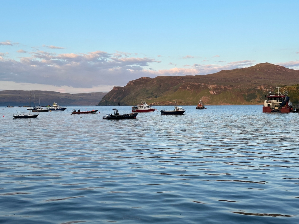 Boats on a calm body of water with hills.