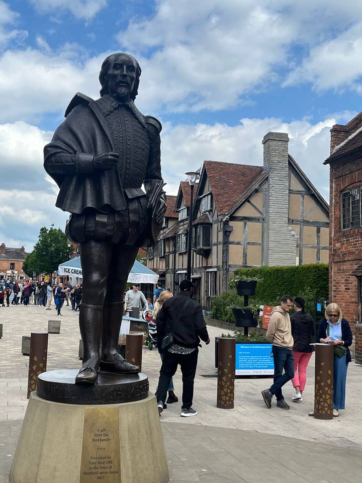 Statue avec des touristes autour d'une rue historique.