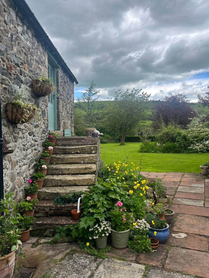 Maison en pierre avec un jardin et des plantes à fleurs.