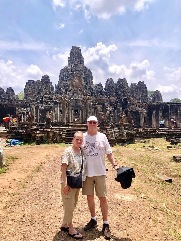 Couple posé devant le temple du Bayon, une ancienne structure en pierre.