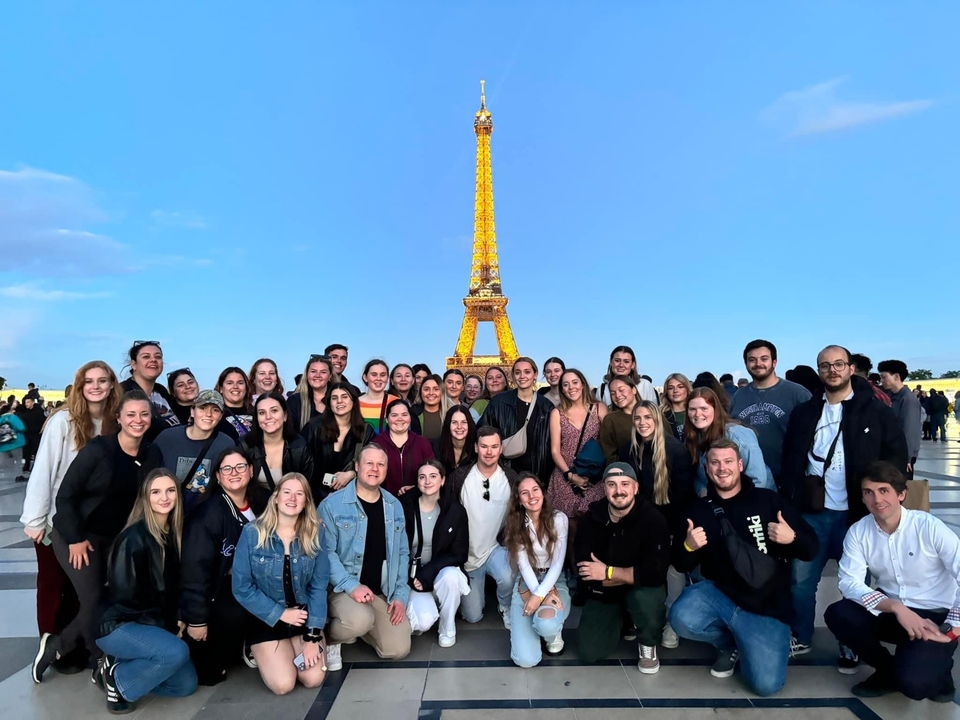 Groupe posant devant la tour Eiffel illuminée.