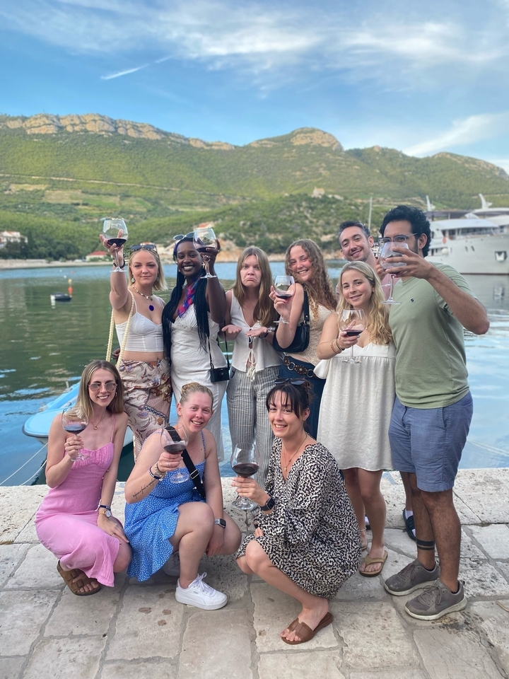 Groupe de personnes tenant des verres de vin, célébrant à l'extérieur.
