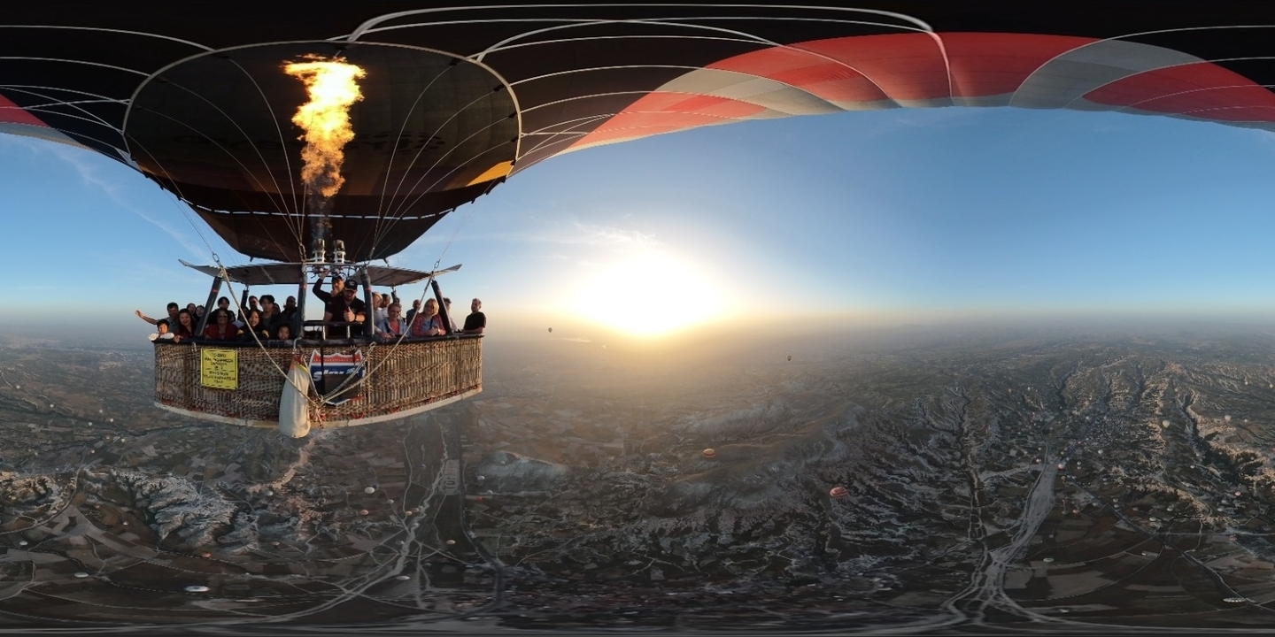 Montgolfière avec des personnes à bord survolant un vaste paysage.