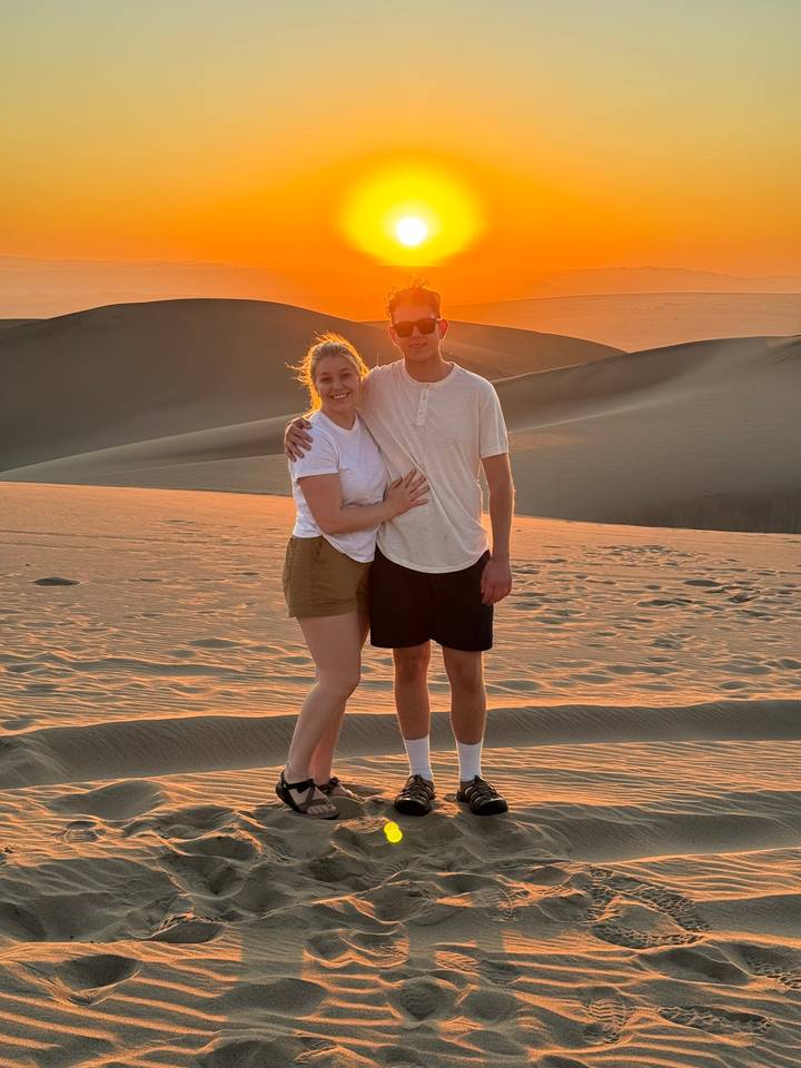Couple posant sur des dunes de sable au coucher du soleil.