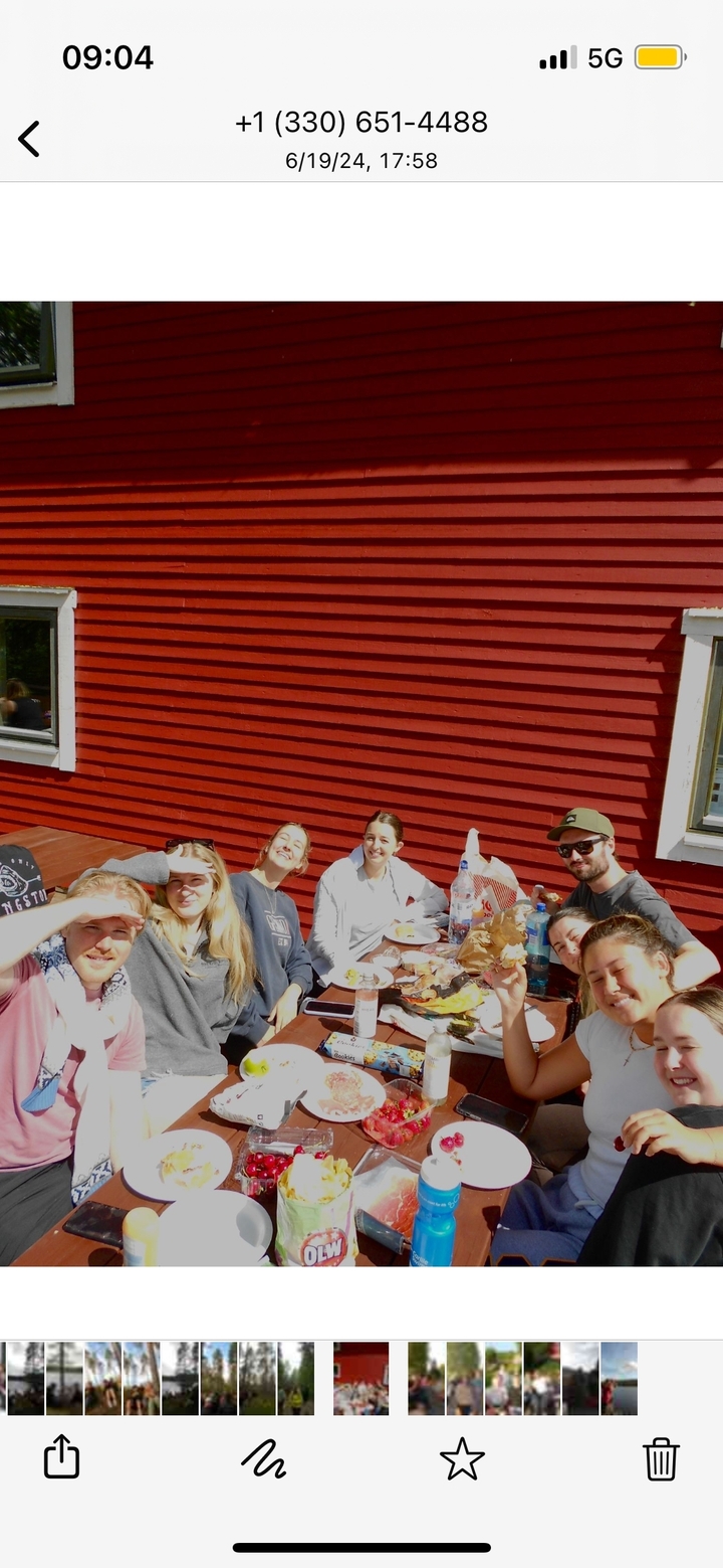 Groupe de personnes profitant d'un repas près d'un mur en bois rouge.