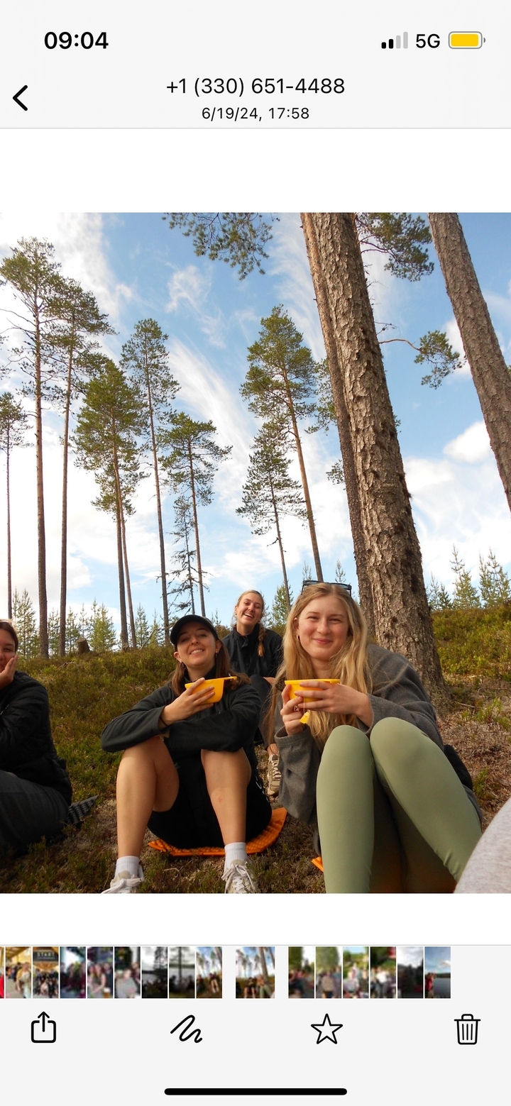 Des personnes souriantes avec de grands arbres en arrière-plan.