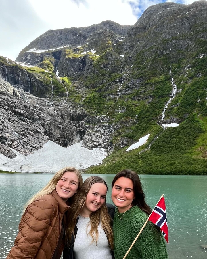 Trois personnes posant avec un arrière-plan montagneux et glaciaire.