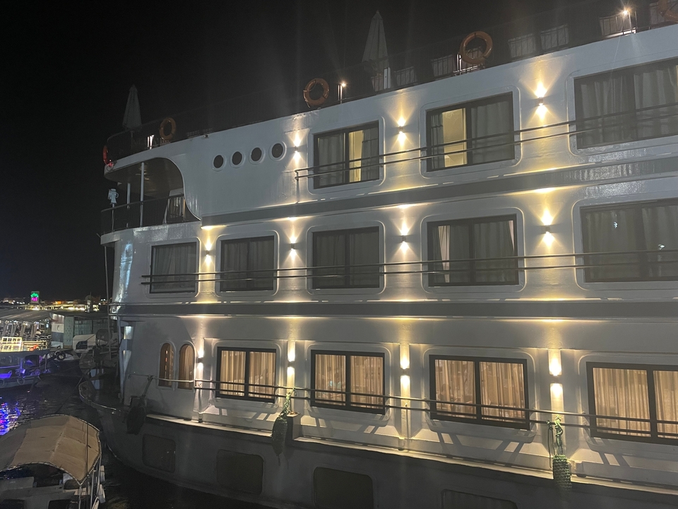 Navire de croisière illuminé la nuit, amarré dans un port.