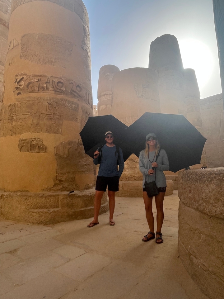 Deux personnes tenant des parapluies à l'intérieur d'un temple ancien.