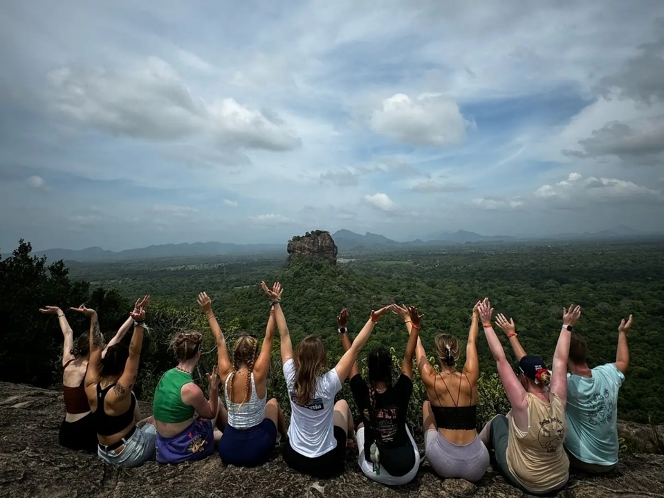 Group of people celebrating with raised hands facing a rock formation.