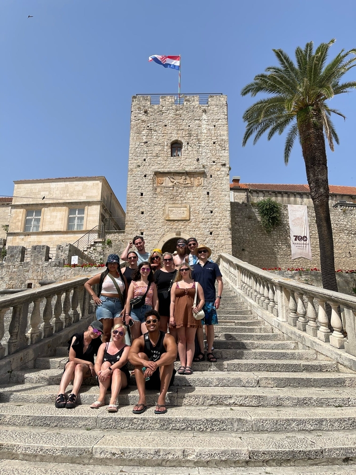 Groupe de personnes sur des escaliers avec une tour de pierre historique.