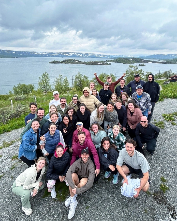 Groupe de touristes prenant la pose avec un fjord et des îles visibles en arrière-plan.