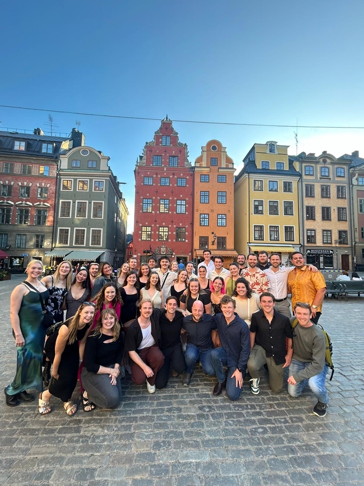 Groupe de personnes devant des bâtiments colorés.