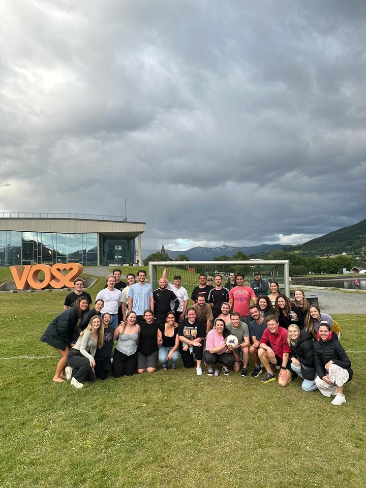 Groupe devant un bâtiment avec une enseigne « Voss ».