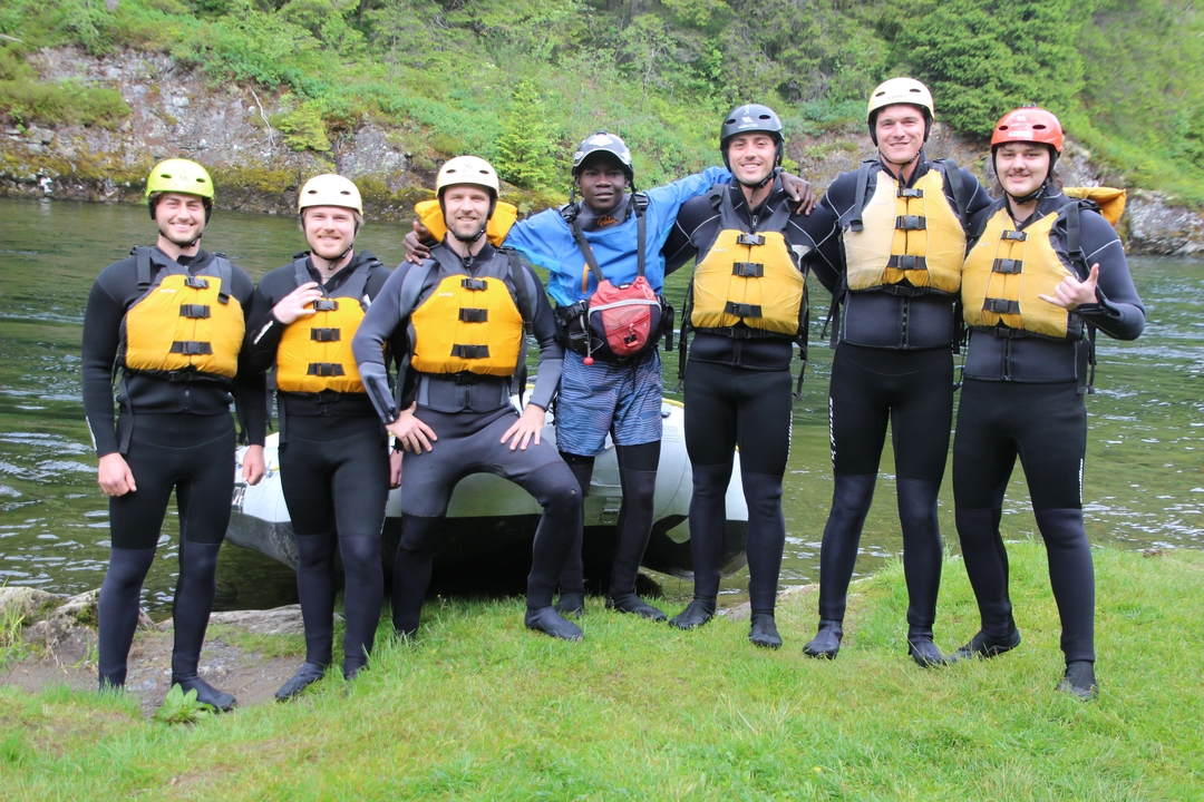 Groupe de personnes en équipement de rafting au bord d'une rivière.