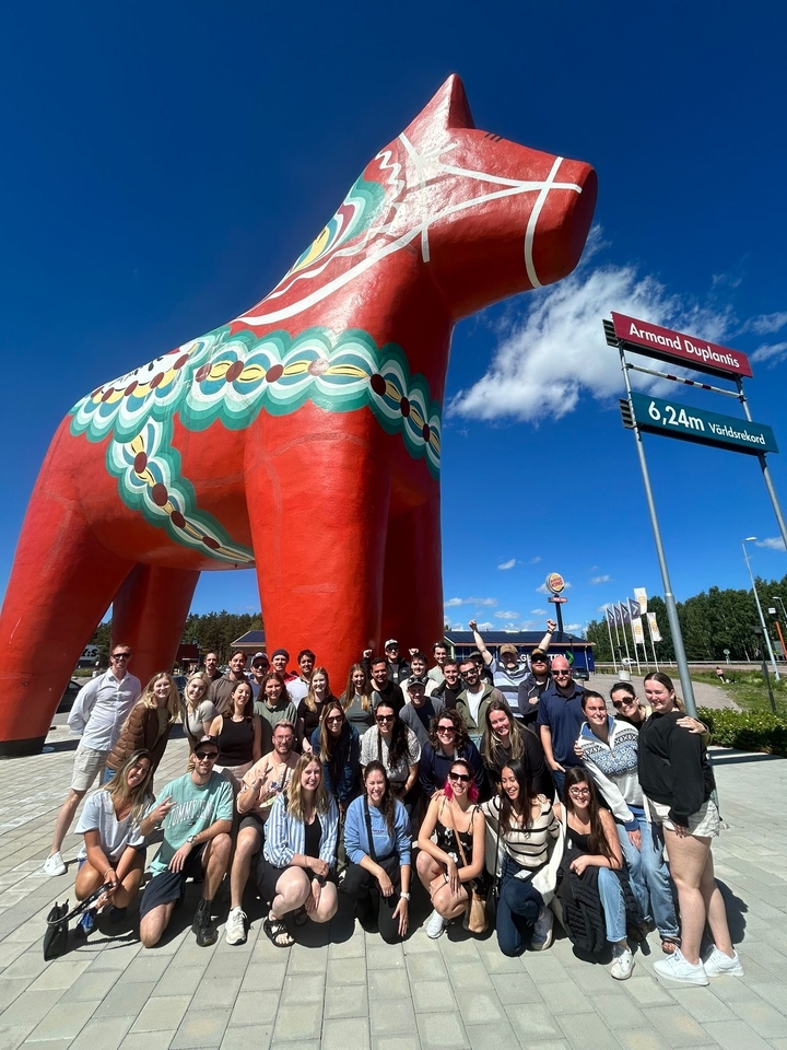 Grand groupe posant avec une statue de cheval de Dalécarlie.