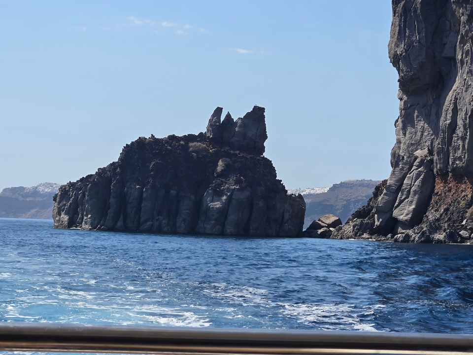 Côte rocheuse avec des falaises sombres et une mer bleue.