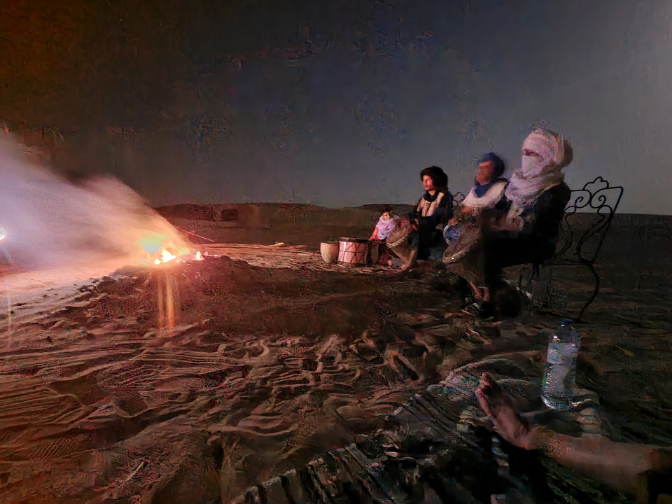 Groupe de personnes assises autour d'un feu de camp dans le désert la nuit.