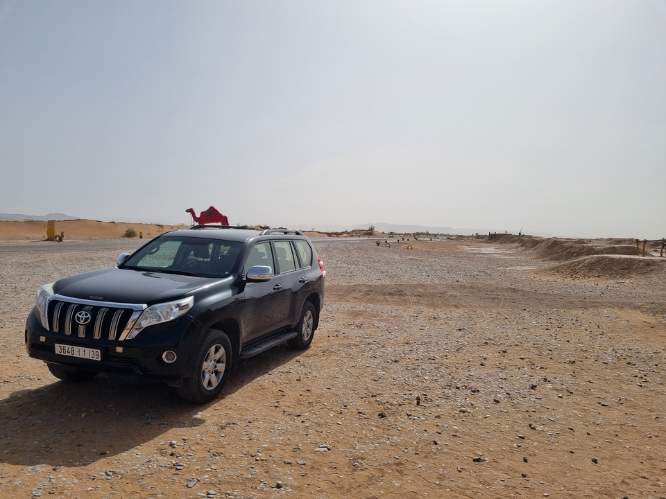 Scène de désert avec un SUV noir et un ornement silhouette de chameau.