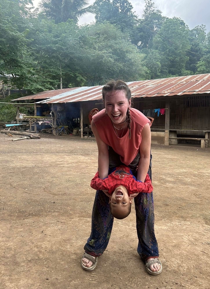 Femme jouant avec un enfant dans un cadre de village rustique.