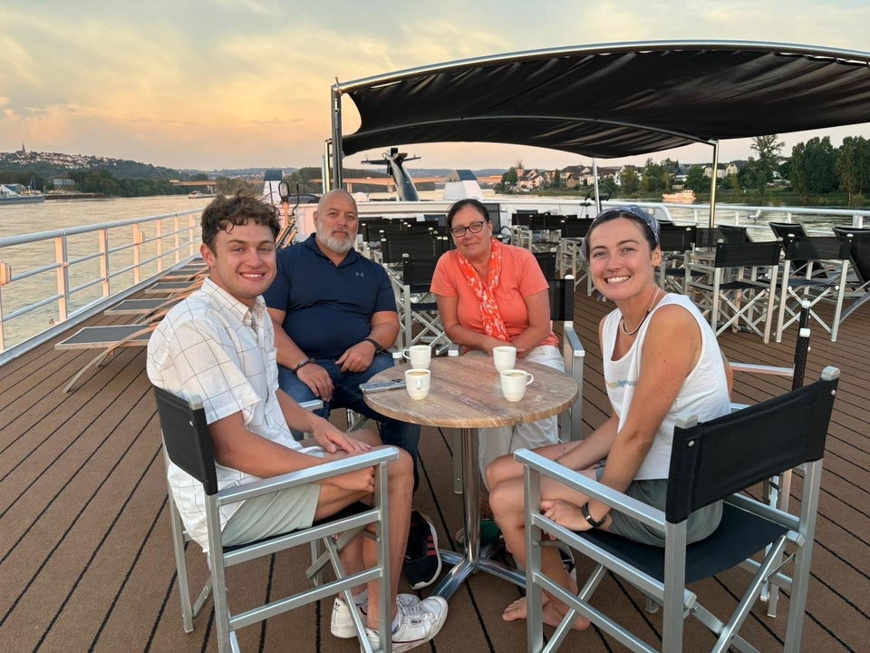Groupe de personnes assises à une table sur le pont d'un bateau.