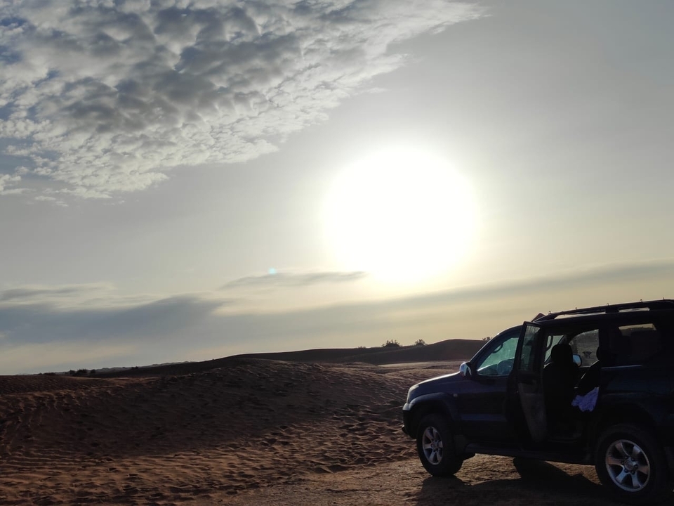 SUV garé sur un paysage désertique avec le soleil couchant.