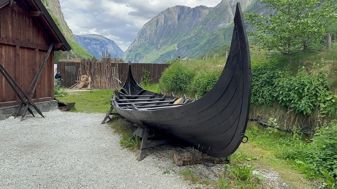 Réplique de navire viking traditionnel entourée d'un paysage montagneux.
