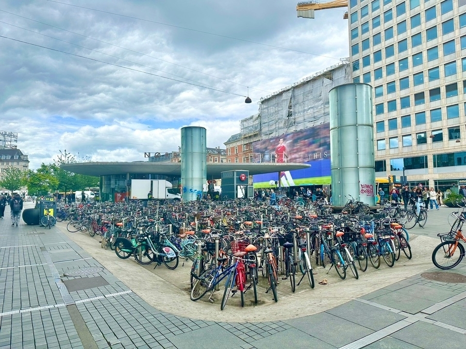 Place de la ville avec de nombreux vélos garés, architecture moderne.