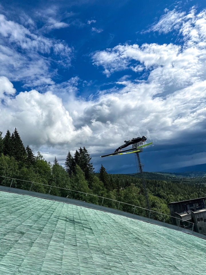 Sauteur à ski en plein vol avec des montagnes en arrière-plan.