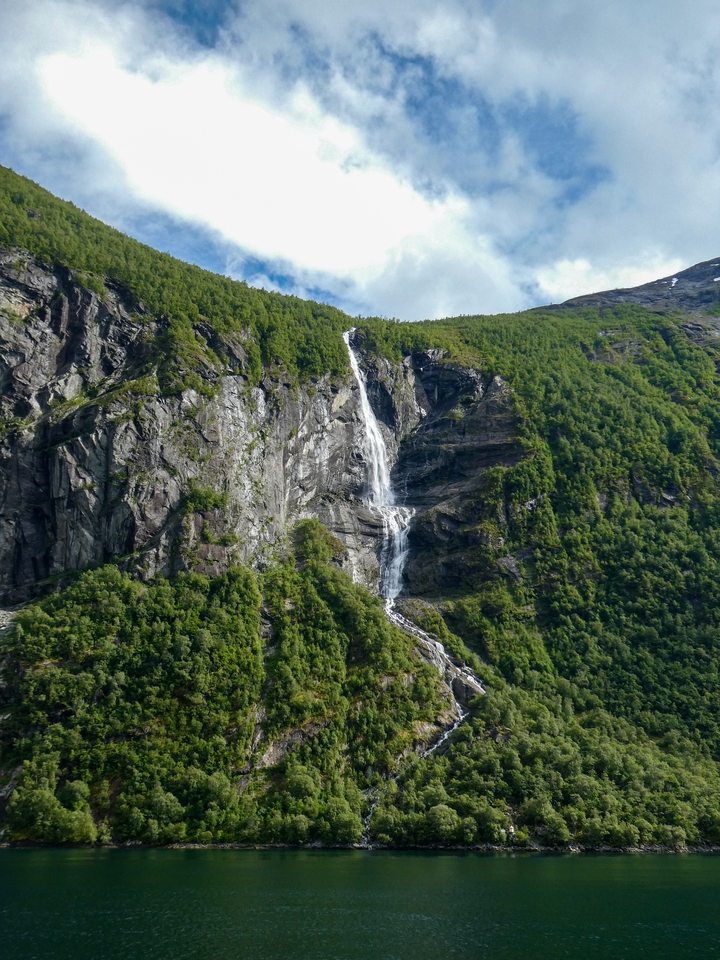 Grande cascade qui dévale une falaise boisée.