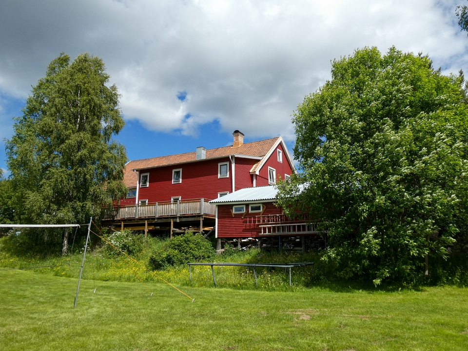 Maison rouge entourée d'une végétation luxuriante.
