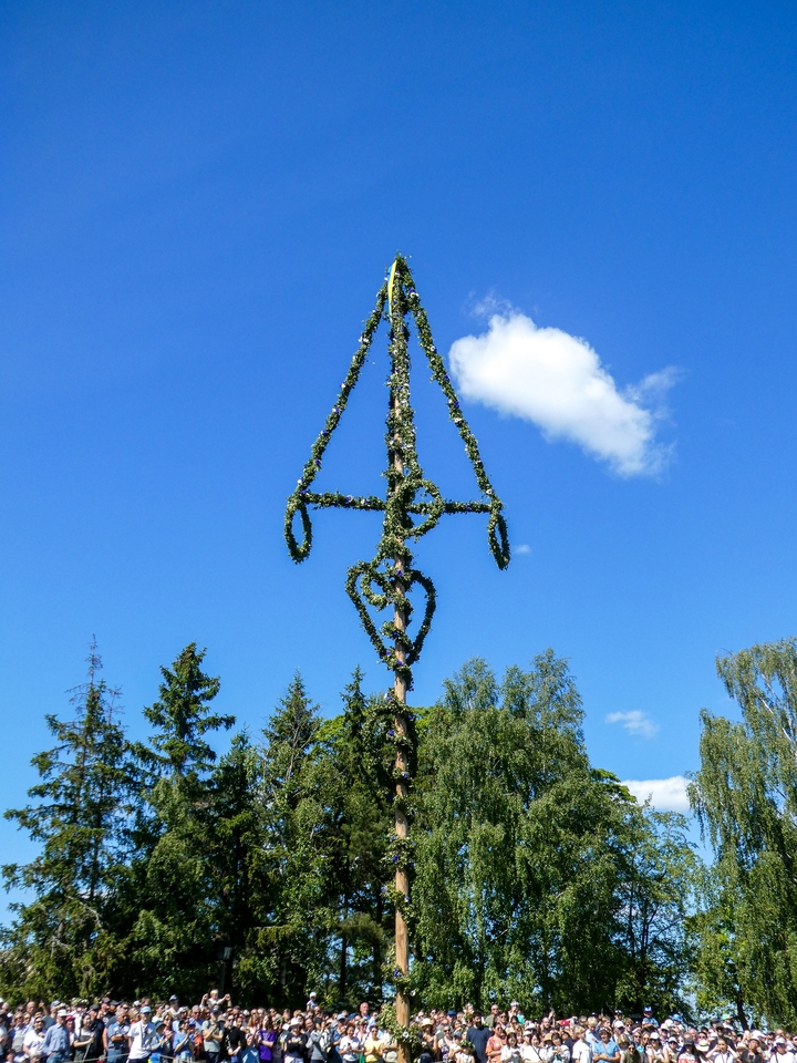 Grand poteau décoré de couronnes contre le ciel bleu.