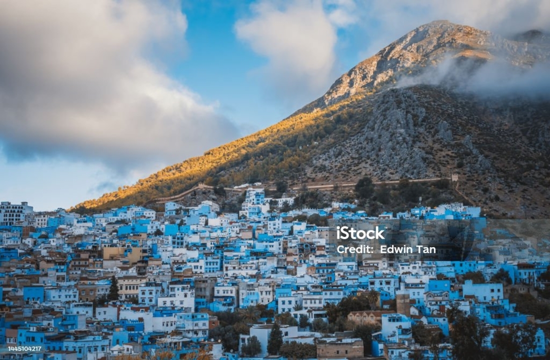 Paysage urbain de bâtiments peints en bleu sous un arrière-plan montagneux.