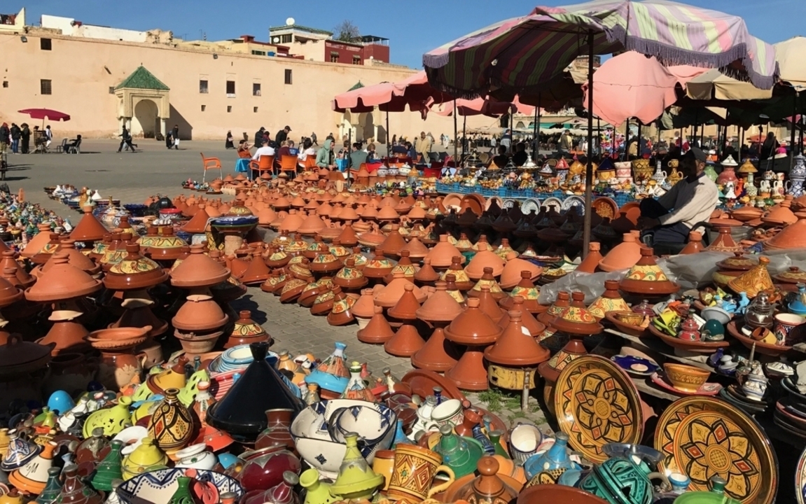 Scène de marché avec poterie traditionnelle et des gens qui font leurs courses.