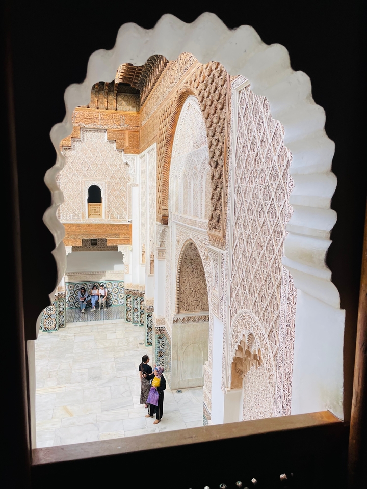 Vue à travers une arche décorée donnant sur une cour.