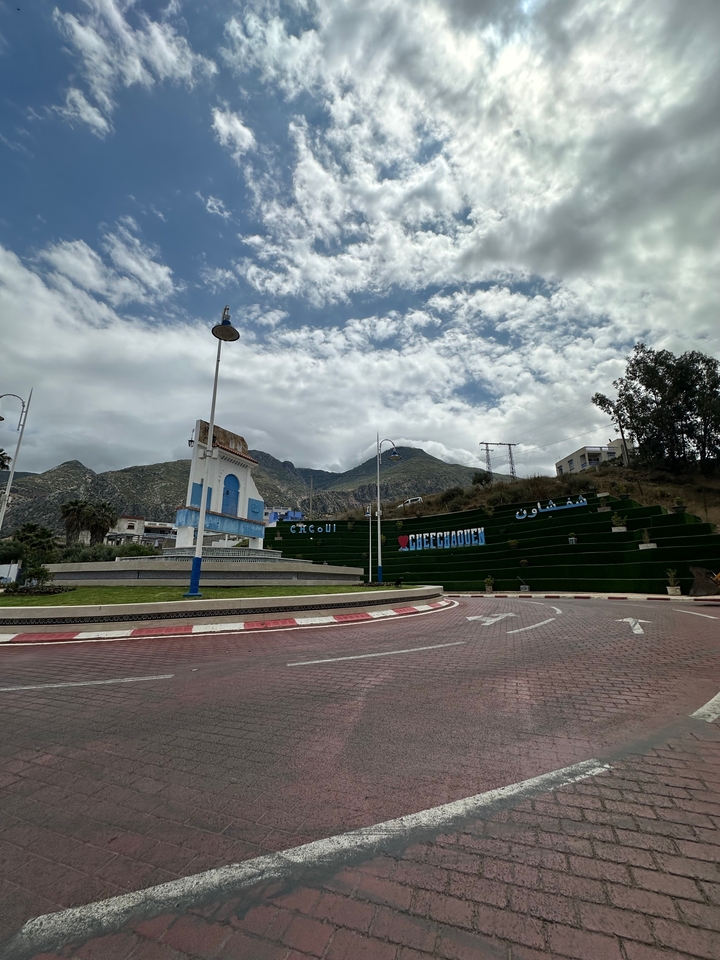 Panneau de bienvenue de la ville avec des montagnes en arrière-plan.