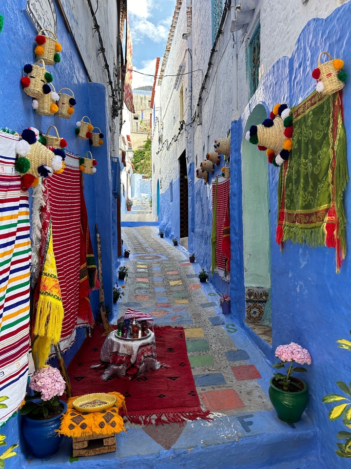 Ruelle aux couleurs vives avec des textiles suspendus dans une rue étroite.