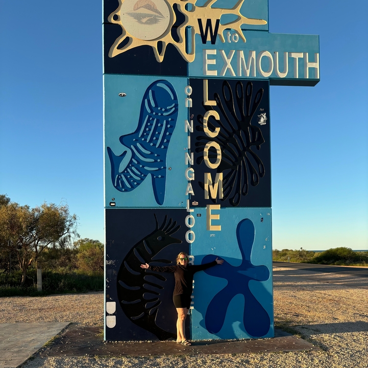 Personne debout près d'un panneau de bienvenue avec des motifs aquatiques.