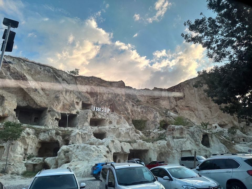 Habitations troglodytiques sous un ciel nuageux avec panneau d'Ürgüp.