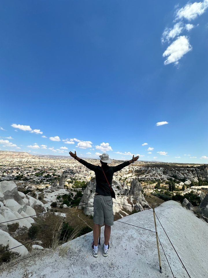 Personne avec les bras levés contemplant un vaste paysage rocheux.