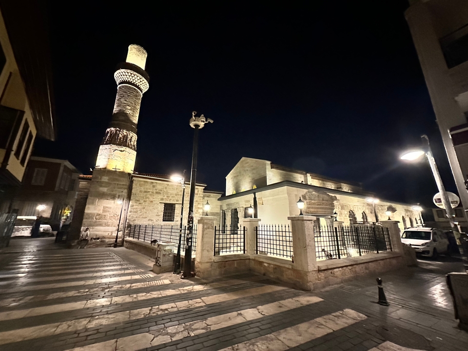 Vue nocturne d'une mosquée avec un minaret et des lampadaires.
