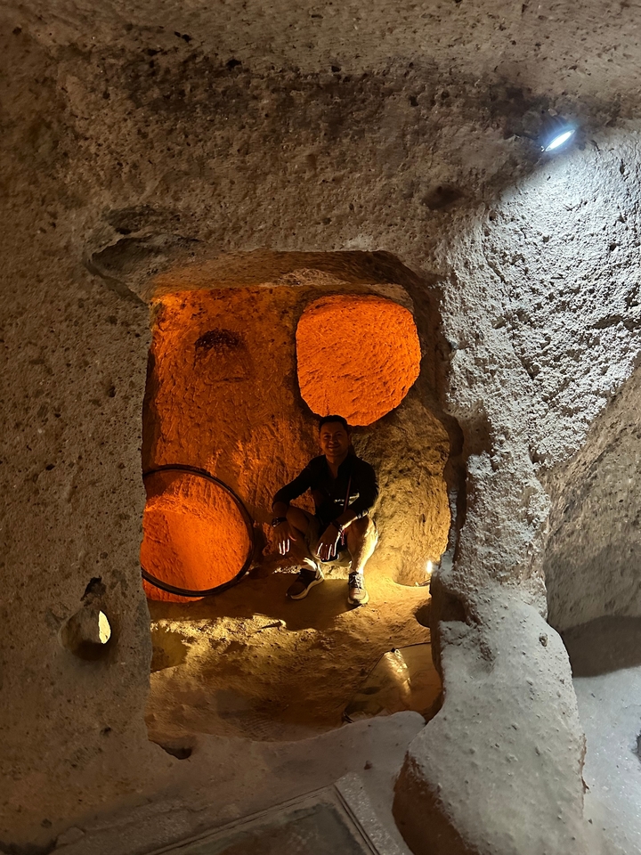 Personne dans une grotte illuminée assise près d'ouvertures rondes.