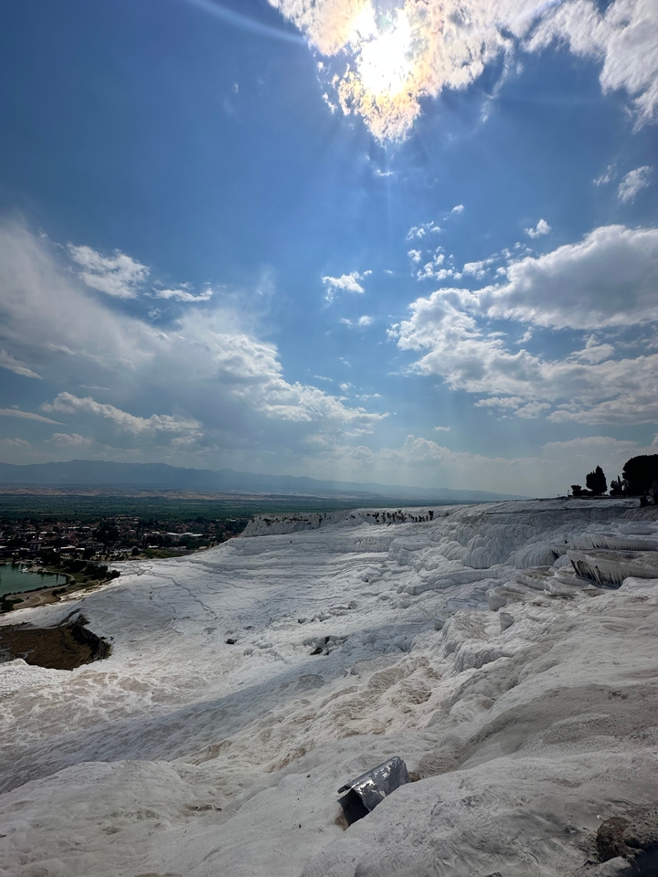 Terrasses de travertin blanc sous un ciel partiellement nuageux.