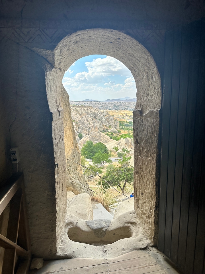 Vue depuis l'intérieur d'une ouverture formée dans la roche au milieu d'un paysage rocheux.