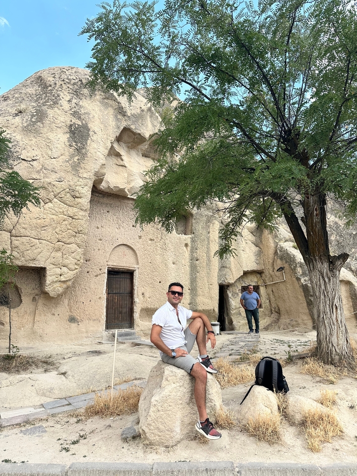 Deux hommes debout devant une structure rocheuse et un arbre.