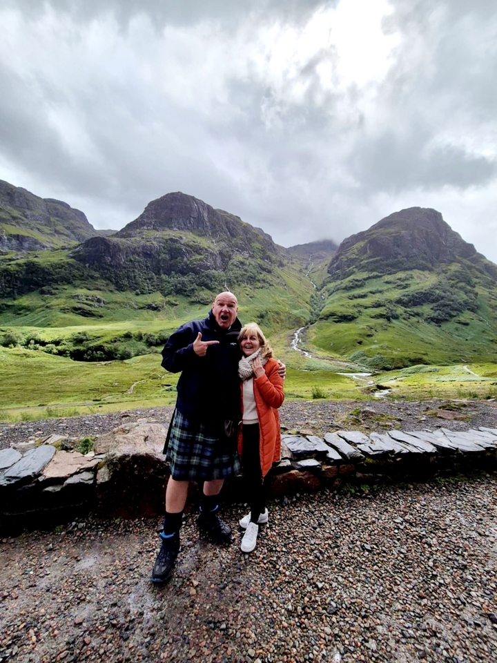 Deux personnes posant avec une vue panoramique sur les collines en arrière-plan.