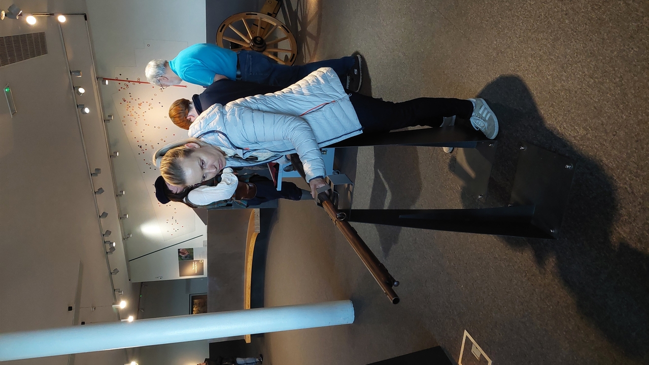 Des personnes interagissant with une exposition de canon historique dans un environnement de musée.