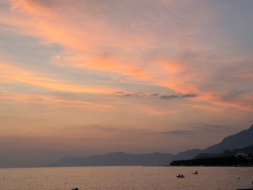 Colorful sunset over mountains and calm sea.