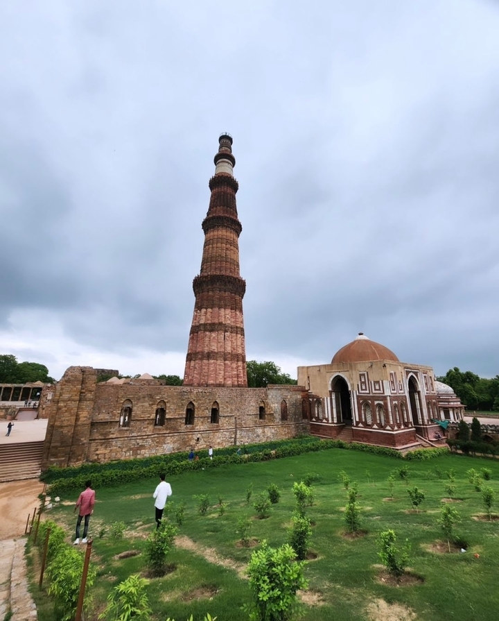 Un grand minaret et une mosquée sous un ciel nuageux.