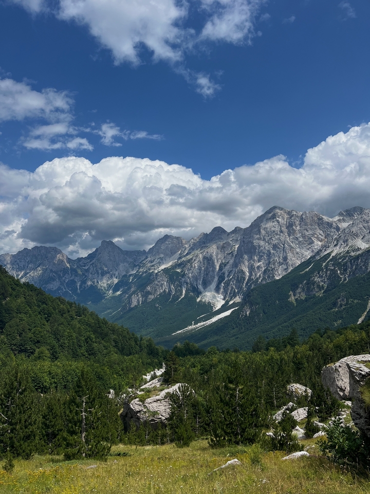 Chaîne de montagnes majestueuse avec des vallées boisées et des nuages spectaculaires.